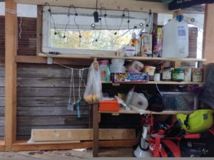 Ein gut gefülltes Regal ist unter einem Fenster mit Lichterkette im Baumhaus zu sehen.